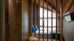 A modern hotel room with a shower, a bed with blue pillows, and a wooden ceiling. - VIP RESIDENCES ANDORRA (El Tarter)