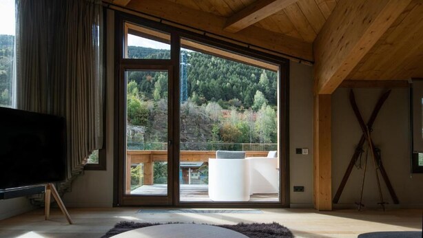 A modern living room with a large TV on a stand, a round coffee table, and a view of a balcony with outdoor furniture. - VIP RESIDENCES ANDORRA (El Tarter)