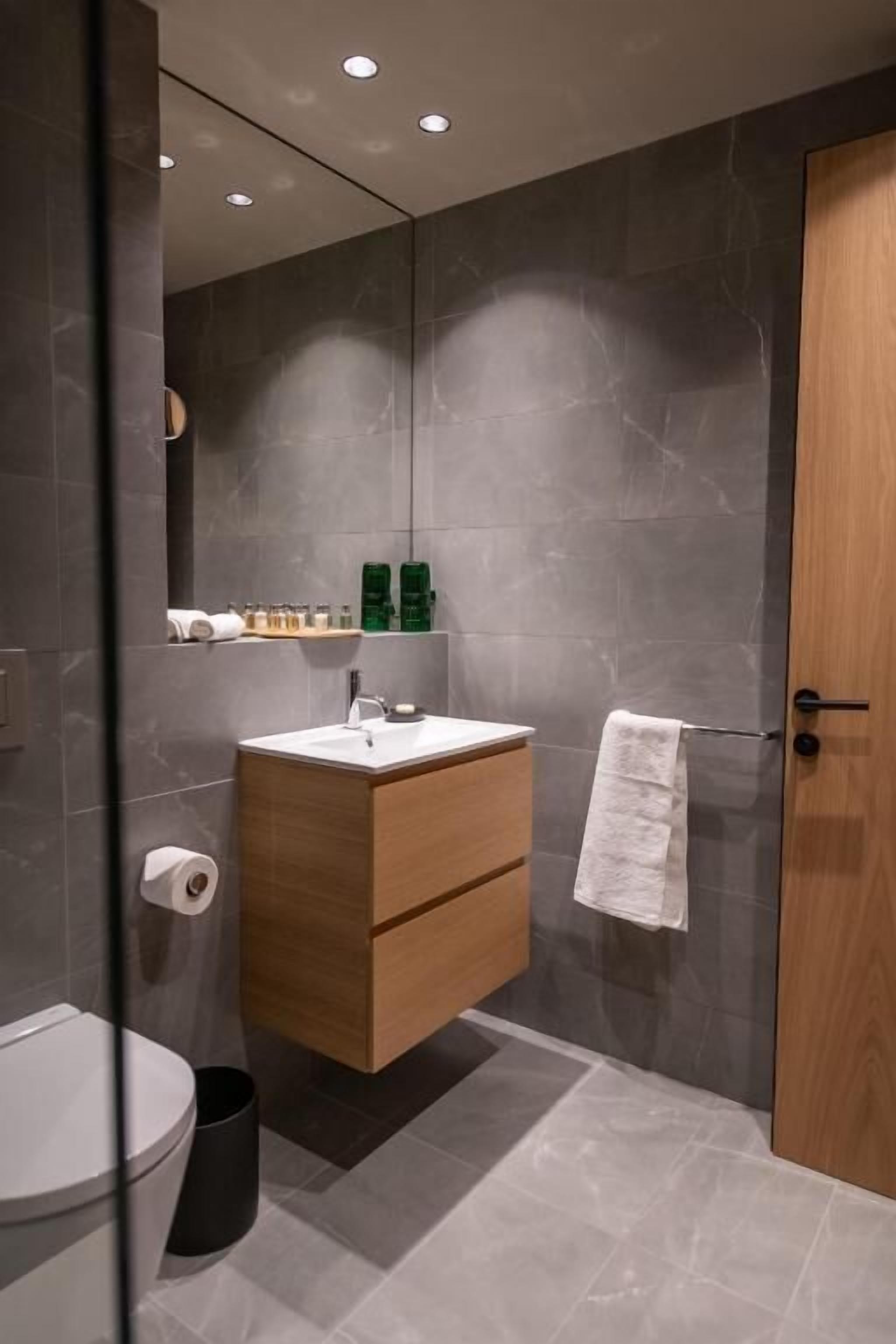 Un baño moderno con un tocador de madera, un espejo y un perchero para toallas.