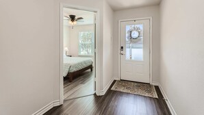 A hallway with a white door, a patterned rug, and a ceiling fan.