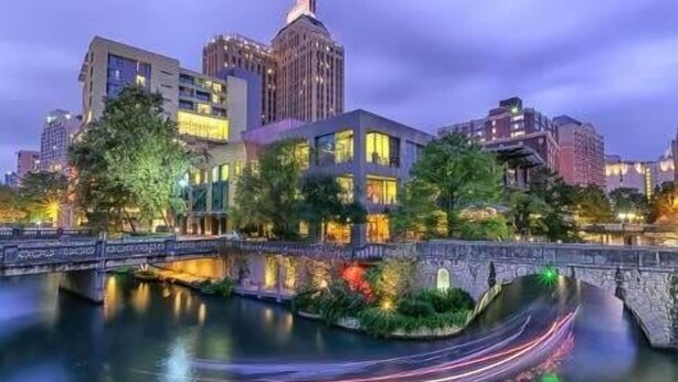 A modern urban area with a river, buildings, and a bridge.