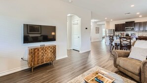 A modern living room with a flat-screen TV, wooden entertainment unit, and a brown leather sofa.