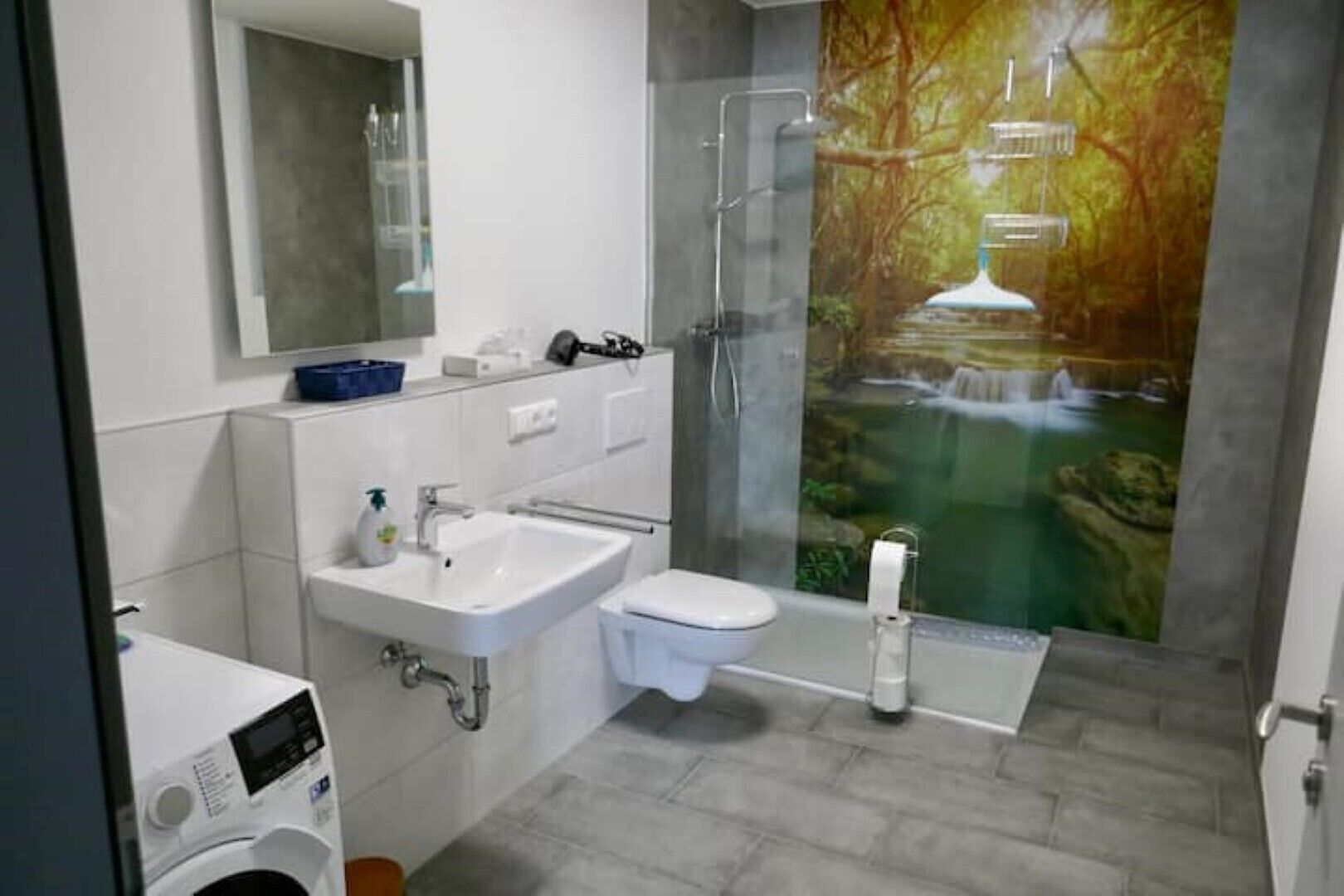 Ein modernes Badezimmer mit Dusche, Toilette, Waschbecken und einem großen Spiegel.