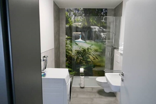 Een moderne badkamer met een douche, toilet en wastafel.