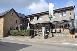Een gebouw met twee verdiepingen, een stenen gevel en een moderne uitbouw.