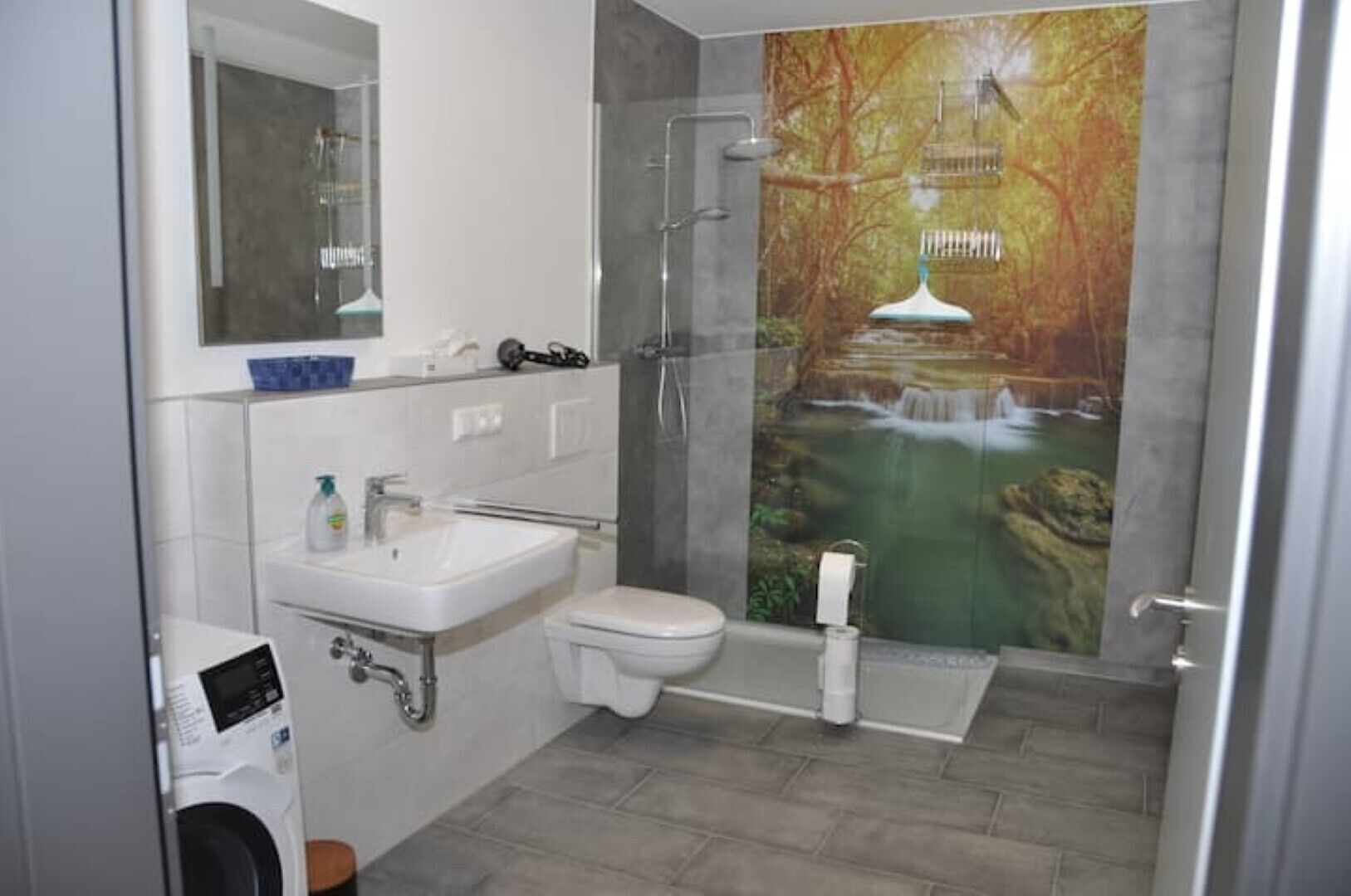 Une salle de bain moderne avec une douche à parois de verre, un lavabo blanc et des toilettes.