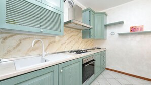 A kitchen with teal cabinets, a white countertop, a gas stove, and an oven.
