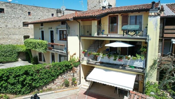 A two-story building with a balcony, a staircase, and a small garden area.