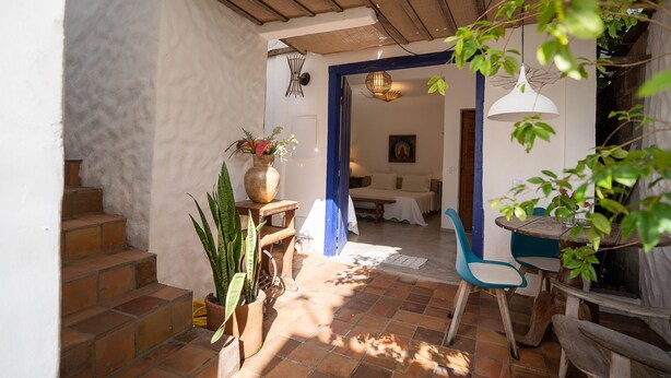 Een gezellig interieur met een trap naar een slaapkamer, een zithoek met een blauwe stoel en een houten tafel.