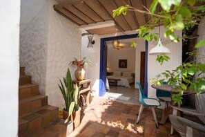 A cozy interior with a staircase leading to a bedroom, a dining area with a blue chair, and a wooden table. - Arandu Casa Hotel Quadrado (Porto Seguro)