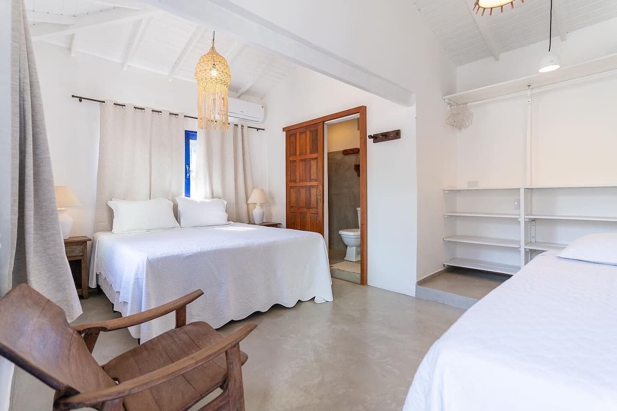 A bedroom with a bed, bedside tables, a wooden chair, a hanging light fixture, and a wardrobe.