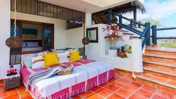 A bedroom with a bed, pillows, a nightstand, a bottle, and a basket.