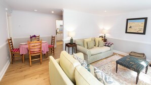 A living room with a dining table, chairs, a sofa, and a patterned rug.