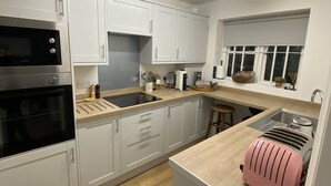 A modern kitchen with white cabinets, a stainless steel oven, a sink, and a pink toaster.