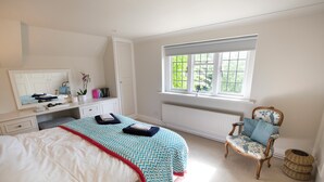 A bedroom with a bed, a chair, a window, and a radiator.