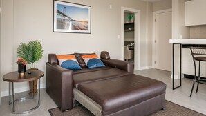 Ein modernes Wohnzimmer mit einem braunen Ledersofa, einem kleinen runden Tisch mit Pflanze und einem gerahmten Bild an der Wand.