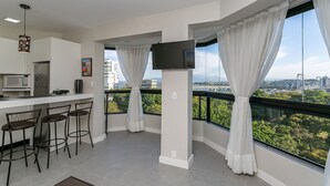 Eine moderne Küche mit Bar, großen Fenstern mit Vorhängen und Blick auf die Stadt.