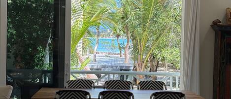 A dining area with a view of palm trees and a pool.