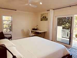A hotel room with a bed, a desk, a chair, and a view of the outdoors.