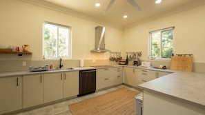 A modern kitchen with white cabinetry, stainless steel appliances, and a large window providing natural light.