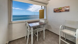 Una habitación pequeña con vista al mar, una mesa, dos sillas y un cuadro en la pared.