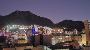 A cityscape at dusk with illuminated buildings and a mountain in the background. - Hotel torre 15  (Bogotá)