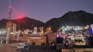 A cityscape at dusk with buildings and a mountain in the background. - Hotel torre 15  (Bogotá)