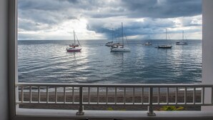 A view of the sea with several sailboats anchored, a beach in the foreground, and a cloudy sky. - Les Pénates - Meublé 3 étoiles - Vue mer (Arrondissement of Saint-Pierre)