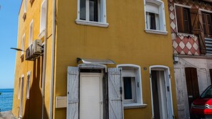 A yellow building with multiple windows and doors, a visible number '30', and a red car parked in front. - Les Pénates - Meublé 3 étoiles - Vue mer (Arrondissement of Saint-Pierre)