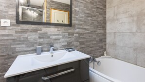 A bathroom with a white sink, a mirror, and a bathtub.