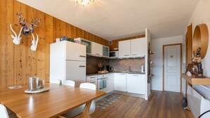 A compact kitchen with white cabinets, a microwave, and a wooden dining table with chairs.