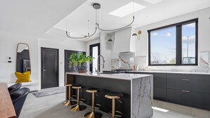 Una cucina moderna con isola in marmo, sgabelli da bar e un'ampia finestra.