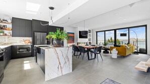 Una cucina moderna con isola in marmo, forno integrato e zona pranzo con una grande finestra che si affaccia sulla città.