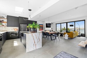 A modern kitchen with a marble island, built-in oven, and a dining area with a large window overlooking the city.