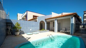 A swimming pool with a tiled deck, a covered seating area, and a potted plant. - Hotel Pousada do Farol (Aracaju)