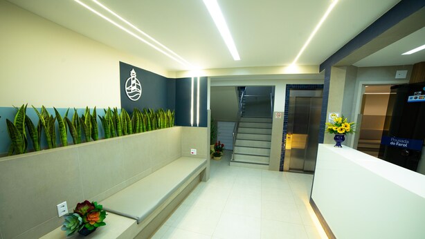 A reception area with a reception desk, a staircase, and a wall-mounted plant display. - Hotel Pousada do Farol (Aracaju)