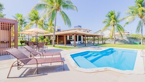 A poolside area with lounge chairs, a covered patio, and a swimming pool. - GB69 Excelente Casa a 400m da Praia (Camaçari)