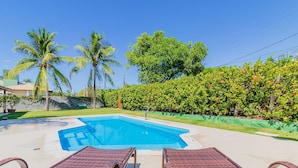 A swimming pool with lounge chairs, surrounded by palm trees and a hedge. - GB69 Excelente Casa a 400m da Praia (Camaçari)