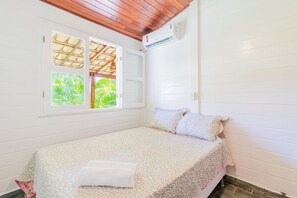 A single bed with a floral bedspread, a white pillow, and a neatly folded white towel. - GB69 Excelente Casa a 400m da Praia (Camaçari)