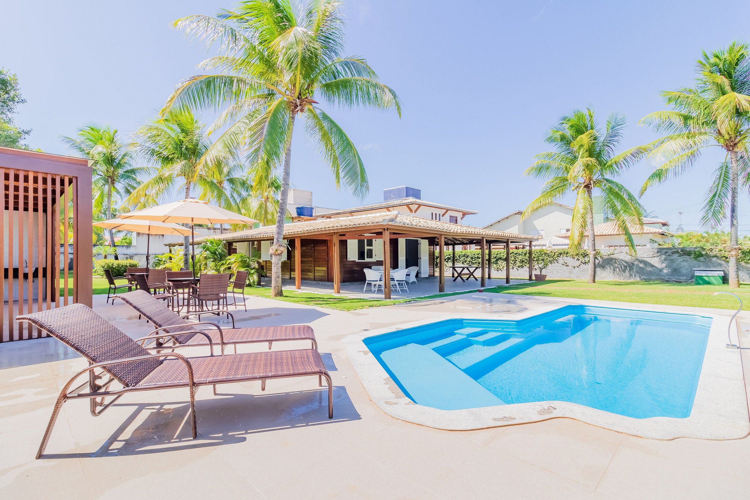 Un espace aménagé au bord de la piscine, avec des chaises longues, un patio couvert et une piscine.