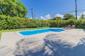 Une piscine à l’eau d’un bleu cristallin, entourée d’une végétation luxuriante et d’une pelouse bien entretenue.