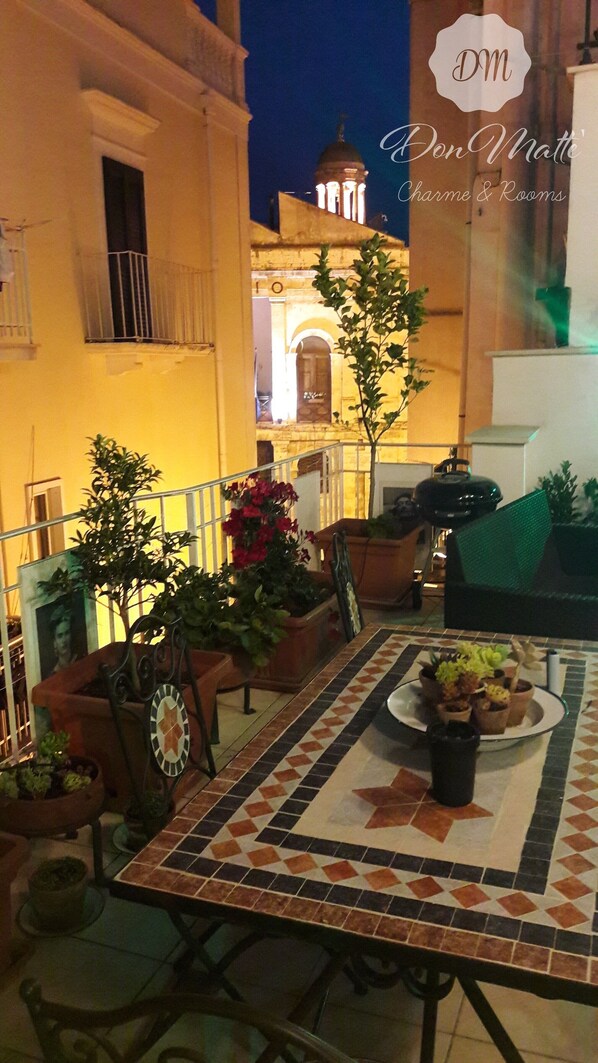 An outdoor patio with a tiled table, potted plants, and a view of a building with a dome in the background.