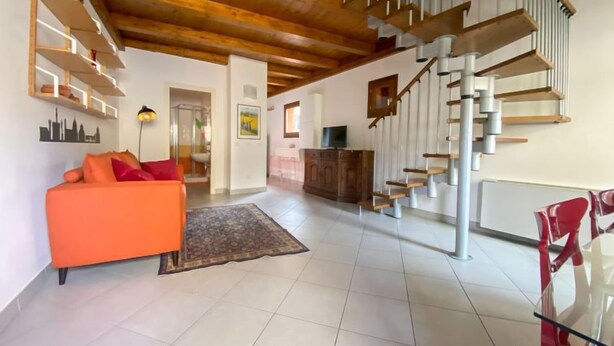 A spacious living area with a modern staircase, a sofa, and a dining table. - Orcagna apartment by Interhome (Florence)