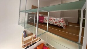 A compact room with a glass balcony, a bed with floral bedding, and a small seating area with cushions. - Orcagna apartment by Interhome (Florence)