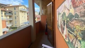A narrow balcony with a white table, a power outlet, and a painting on the wall. - Orcagna apartment by Interhome (Florence)