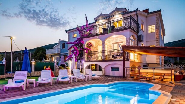A large house with a swimming pool, lounge chairs, and a covered patio area. - Vacation home Josipa by Interhome (Kaštela)
