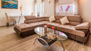 A modern living room with a sectional sofa, a glass coffee table, and a painting on the wall. - Vacation home Josipa by Interhome (Kaštela)