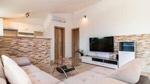 A modern living room with a beige sofa, a glass coffee table, and a flat-screen TV on a white entertainment unit. - Vacation home Josipa by Interhome (Kaštela)