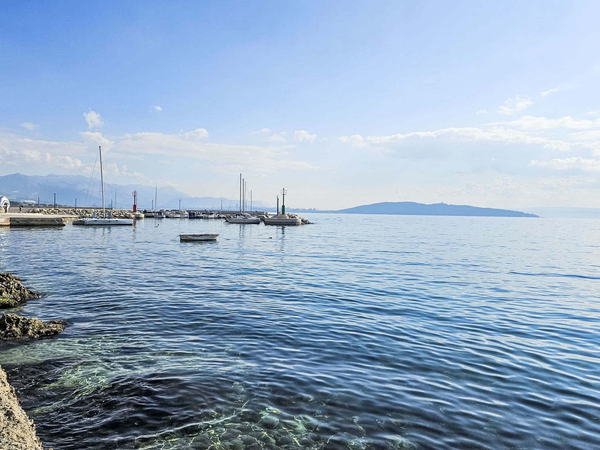 Un puerto deportivo con barcos amarrados, agua tranquila y cielo despejado.