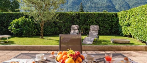 Un espace de restauration en plein air avec une table dressée pour le petit-déjeuner, offrant une vue sur un paysage montagneux.